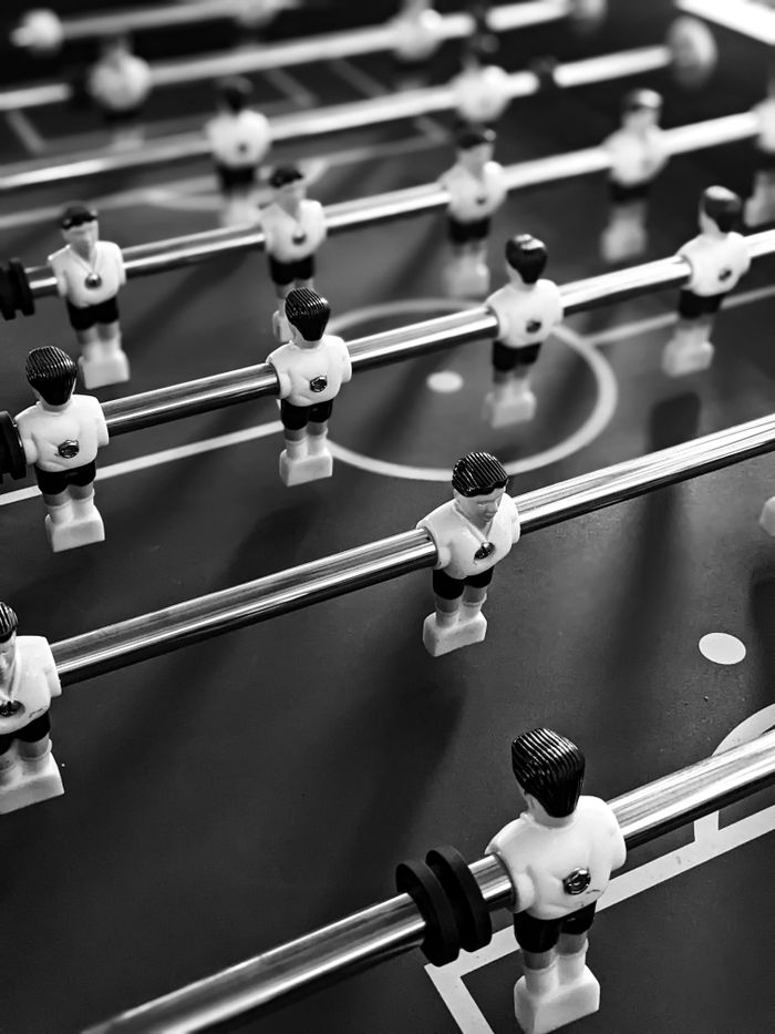 Monochromatic close-up of foosball players symbolizing teamwork.